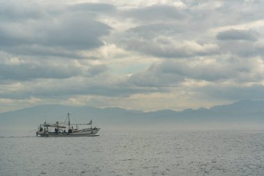 15 Şubat 2024 'te Japonya' da Osaka Körfezi 'nde bulutlu bir gökyüzünün altında sakin bir denizde yalnız bir balıkçı teknesi.