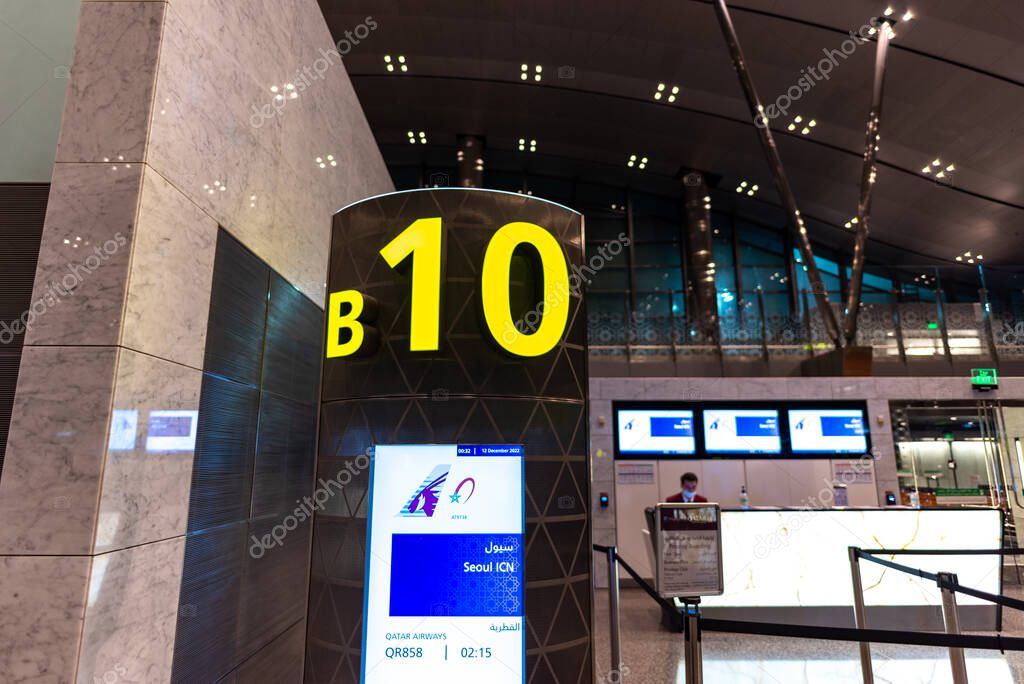 Airport boarding gate B10 with digital display showing flight details for Qatar Airways flight to Seoul Incheon airport, at Hamad International Airport in Doha, Qatar on 12 December 2022