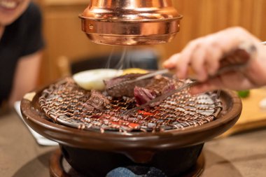 Kore barbekü ızgarasında maşayla et pişirirken yakın plan çekimler.