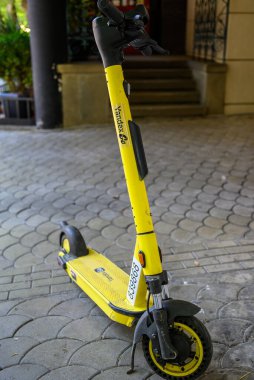 Sarı Yandex elektrikli scooter 21 Nisan 2025 'te Tiflis, Georgia' da bir şehir sokağına park edildi.