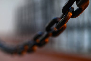 Ilık ışıklandırmada arka planı bulanık olan metal bir zincirin yakın çekimi.