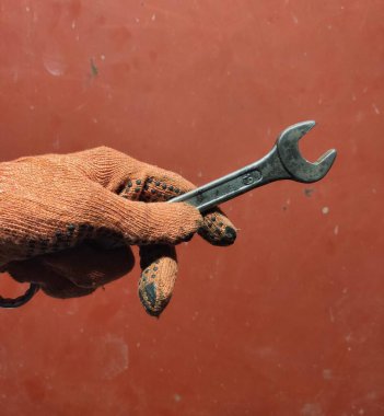 hand holding a wrench on a red background