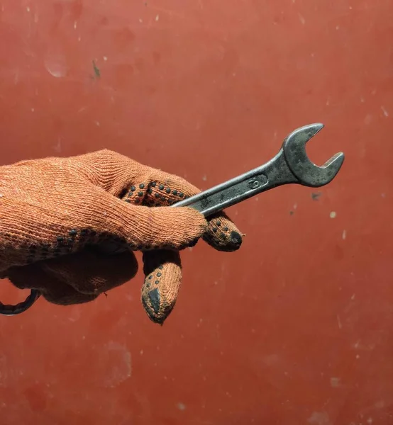 hand holding a wrench on a red background