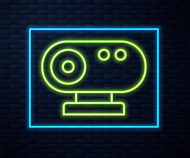 Parlayan neon hattı web kamera ikonu tuğla duvar arka planında izole edildi. Sohbet kamerası. Web kamerası simgesi. Vektör.