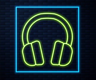 Parlayan neon hattı kulaklık simgesi tuğla duvar arkasında izole edilmiş. Kulaklıklar. Müzik, hizmet, iletişim ve operatör konsepti. Vektör