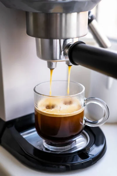 Making coffee with an espresso machine at home, Glass cup of americano on the kitchen table
