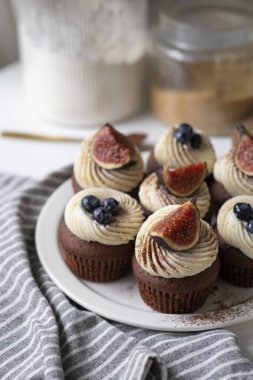 Krem peynirli çikolatalı kekler, incir dilimleri, yabanmersini ve kakao tozu..