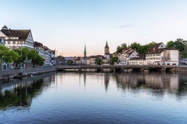Limmat nehrinin üzerindeki Kirche Fraumunster ve Aziz Peter Kilisesi manzaralı Zürih eski kasaba gündoğumu. 26 Mayıs 2024 'te İsviçre' nin Zürih kentinde çekildi.