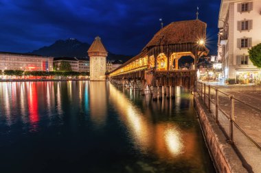 the view of chapel bridge over the Reuss river at night when the bridge is lit up. Famous landmark in Lucerne, Switzerland. Taken on May 27 2024 clipart