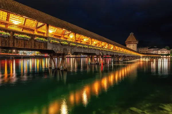 stock image the view of chapel bridge over the Reuss river at night when the bridge is lit up. Famous landmark in Lucerne, Switzerland. Taken on May 27 2024