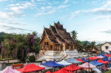 Luang Prabang Ulusal Müzesi 'ndeki Haw Phra Bang tapınağının yerel Gece Pazarı manzarası. Gün batımında çekilmiş. Luang Prabang, Laos