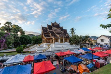 Luang Prabang Ulusal Müzesi 'ndeki Haw Phra Bang tapınağının yerel Gece Pazarı manzarası. Gün batımında çekilmiş. Luang Prabang, Laos 28 Ekim 2024
