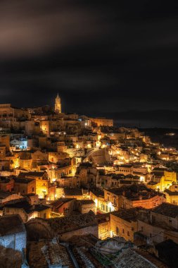 Sassi di Matera 'nın gece manzarası. Birbirine bağlı geniş mağara evleri dar sokaklar boyunca. Matera, İtalya 'da ünlü ikonik cazibe