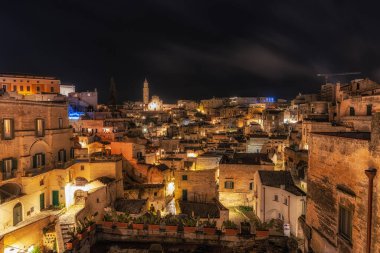 Sassi di Matera 'nın gece manzarası. Birbirine bağlı geniş mağara evleri dar sokaklar boyunca. Matera, İtalya 'da ünlü ikonik cazibe