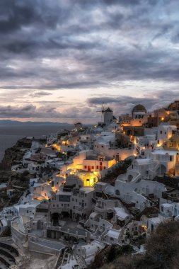 Oia Santorini 'nin günbatımı manzaralı ünlü beyaz renkli sahil köyü. Yunanistan 'ın Santorini kentinde ünlü günbatımı sahnesi çekildi
