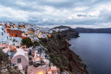 Oia Santorini 'nin gündoğumu manzarası. Uçurumun kenarındaki ünlü beyaz renkli sahil köyü. Yunanistan 'ın Santorini kentinde ünlü gündoğumu noktası alındı