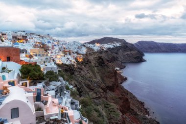 Oia Santorini 'nin gündoğumu manzarası. Uçurumun kenarındaki ünlü beyaz renkli sahil köyü. Yunanistan 'ın Santorini kentinde ünlü gündoğumu noktası alındı