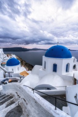 Sunrise view over blue domed church in Santorini along narrow alleyways. Taken in Oia, Santorini clipart