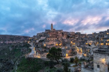 Sassi di Matera 'nın günbatımı manzarası. Birbirine bağlı geniş mağara evleri dar sokaklar boyunca. Matera, İtalya 'da ünlü ikonik cazibe