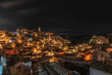 Sassi di Matera 'nın gece manzarası. Birbirine bağlı geniş mağara evleri dar sokaklar boyunca. Matera, İtalya 'da ünlü ikonik cazibe