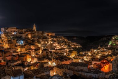 Sassi di Matera 'nın gece manzarası. Birbirine bağlı geniş mağara evleri dar sokaklar boyunca. Matera, İtalya 'da ünlü ikonik cazibe