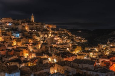 Sassi di Matera 'nın gece manzarası. Birbirine bağlı geniş mağara evleri dar sokaklar boyunca. Matera, İtalya 'da ünlü ikonik cazibe