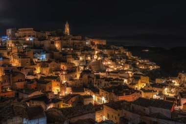 Sassi di Matera 'nın gece manzarası. Birbirine bağlı geniş mağara evleri dar sokaklar boyunca. Matera, İtalya 'da ünlü ikonik cazibe