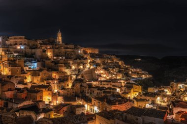 Sassi di Matera 'nın gece manzarası. Birbirine bağlı geniş mağara evleri dar sokaklar boyunca. Matera, İtalya 'da ünlü ikonik cazibe