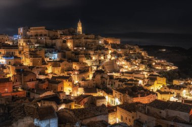 Sassi di Matera 'nın gece manzarası. Birbirine bağlı geniş mağara evleri dar sokaklar boyunca. Matera, İtalya 'da ünlü ikonik cazibe