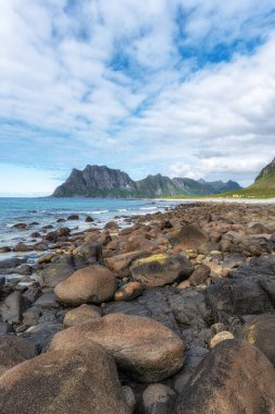 Yazın kayalık kıyı oluşumlarıyla Uttakleiv plajı. Norveç 'in Lofoten adalarındaki ünlü plaj.