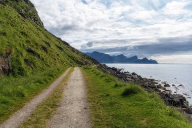 Yazın kayalık kıyı oluşumlarıyla Uttakleiv sahil yolu. Norveç 'in Lofoten adalarındaki ünlü plaj.