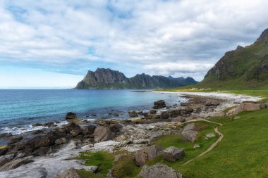 Yazın kayalık kıyı oluşumlarıyla Uttakleiv plajı. Norveç 'in Lofoten adalarındaki ünlü plaj.