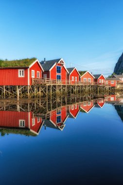 Reine 'de kırmızı rorbu kulübeleri, Norveç yaz boyunca suyun yansımalar için sakin olduğu zamanlarda çekildi.