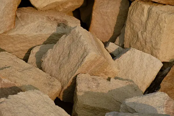 İnşaat ve peyzaj için kullanılan kabaca kesilmiş bej taşların yakın çekim görüntüsü  