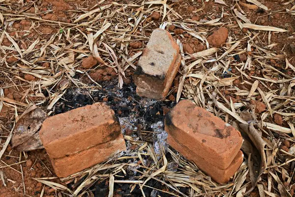 Açık hava kamp ateşi, yanmış tuğlalar, mangal kömürü külleri ve kuru bambu yaprakları ile Kızıl Toprakta
