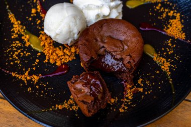 Dondurma toplarıyla servis edilen bir tabak lezzetli, sıcak çikolatalı kek. Süslü tabakta lav keki. Yüksek kalite fotoğraf
