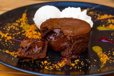 Dondurma toplarıyla servis edilen bir tabak lezzetli, sıcak çikolatalı kek. Süslü tabakta lav keki. Yüksek kalite fotoğraf