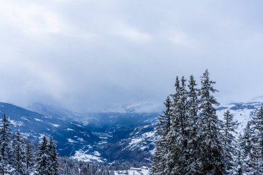Kayak merkezine uzaklıktan bak. Dağ vadisi, ladin ağaçları, bulutlu gökyüzü. Fransız Alpleri 'nde dağın tepesinden güzel panoramik manzara. Yüksek kalite fotoğraf