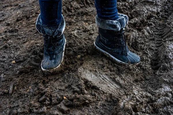Childs feet in dirty stained boots, muddy background. Dirty in the mud warm boots. Hight quality photo