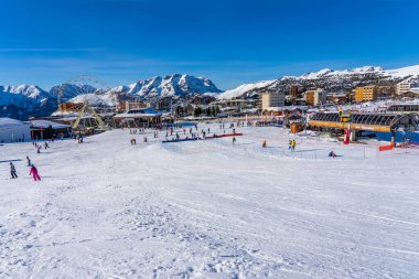 Alpe D 'Huez, FRANCE - 01.01.2022: Fransa, Avrupa' daki ünlü kayak merkezi. Dağda kayak yapan kayakçılar, kayak kaldıranlar, aile sporları, kar dağları konseptinde tatiller. Kış zamanları