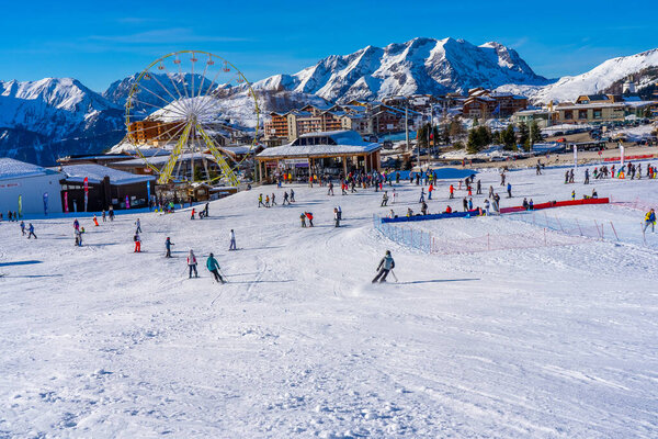 Alpe D'Huez, FRANCE - 01.01.2022: Famous ski resort in French Alps, France, Europe. Skiers skiing on the mountain, ski lift, family sports weekend, holidays in the snow mountains concept. Winter times