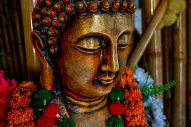 Bronz Buda heykelinin kapağı, festival töreni için çiçek süslemeleriyle meditasyonda duruyor. Yüksek kalite fotoğraf