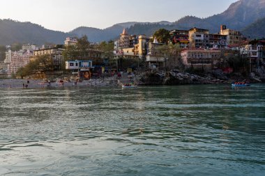 Rishikesh, Uttarakhand, Hindistan - 28.03.2023: Rishikesh 'teki Güzel Ganga Nehri Ashram ve tapınak binalarıyla çevrili. Tamamen temiz nehir suyu. Yüksek kalite fotoğraf