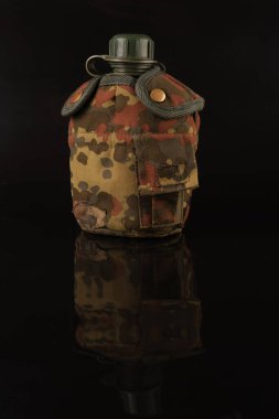 Siyah arka planda yansıması olan kamuflaj kapağında yeni olmayan plastik bir ordu.