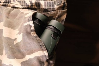 Kamuflaj askeri pantolonun cebindeki yeşil dürbünü kapat.