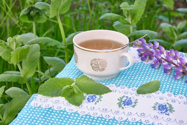 drink tea from mint plants in a mug in the garden on a tablecloth with flowers. Natural. Mint leaves