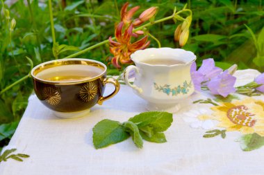 Açık havada nane çayı kupalar, zambak çiçekleri.