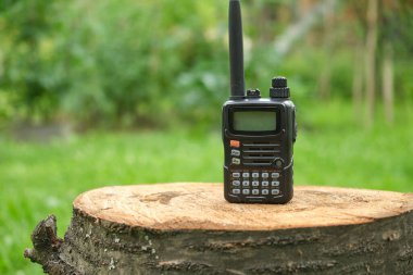 professional black walkie talkie in nature on a tree stump