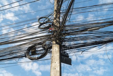 Busy high voltage cables with the cable on the electric pole on the sky background, the tangled electric cable will make the short circuit to cause fire