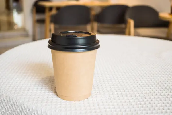 A watercolor coffee mug based on a black lid is placed on a white tablecloth. The pogas black coffee mug does not add brown blurred background. Coffee contains caffeine to keep the body awake.